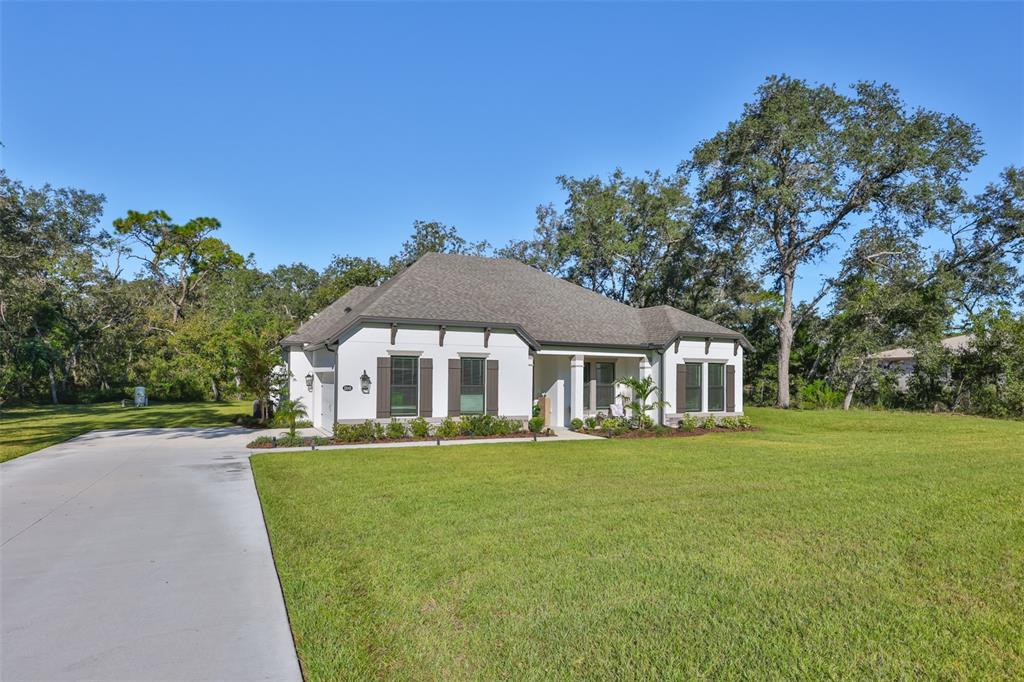 A white single-story house with a gray roof sits on a large grassy lot — 13148 OLDENBURG DRIVE, HUDSON, FL