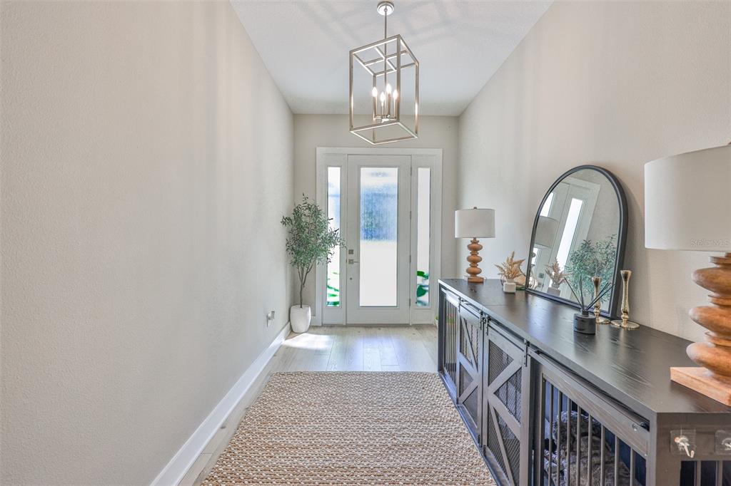 A bright entryway features a light wood floor, a woven rug, and a metal lantern pendant — 13148 OLDENBURG DRIVE, HUDSON, FL