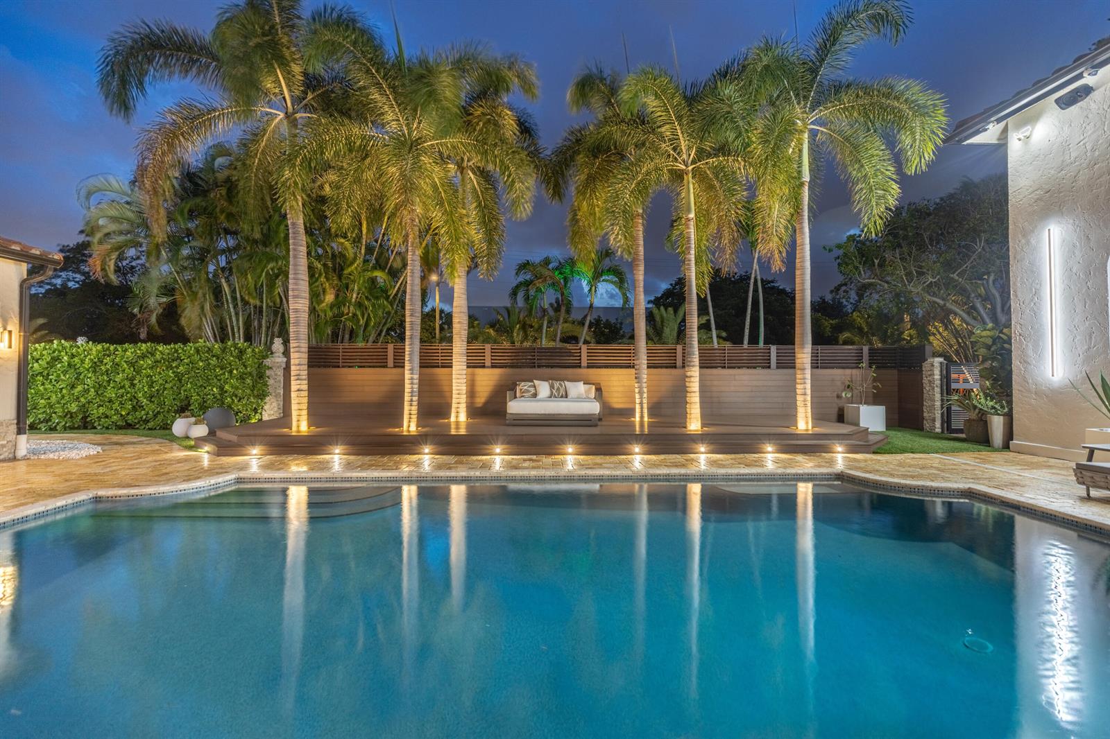 A swimming pool sits in front of a wooden deck with palm trees and seating — 290 NW 6th Street, Boca Raton FL 33432, BOCA RATON, FL