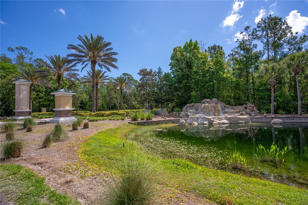 A landscaped park area features a small pond with a rock waterfall and palm trees — 606 GRAND RESERVE DRIVE, BUNNELL, FL