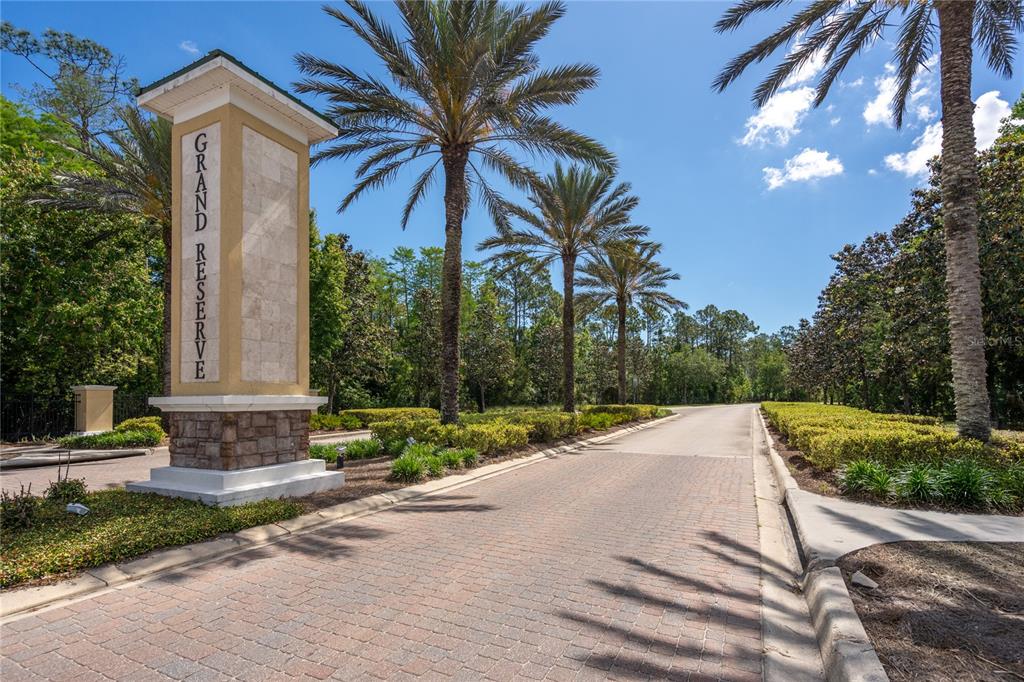 A stone monument sign for Grand Reserve stands at the entrance of a paved road — 606 GRAND RESERVE DRIVE, BUNNELL, FL