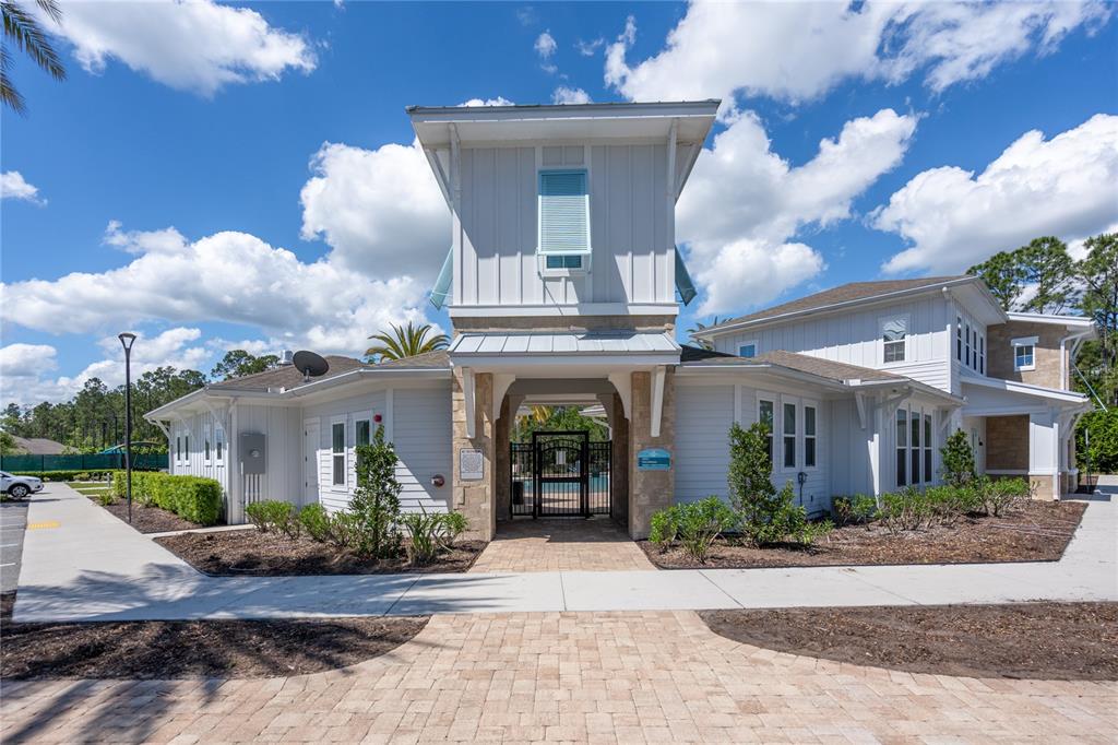 A light-colored building with a central tower and stone accents stands under a blue sky — 606 GRAND RESERVE DRIVE, BUNNELL, FL