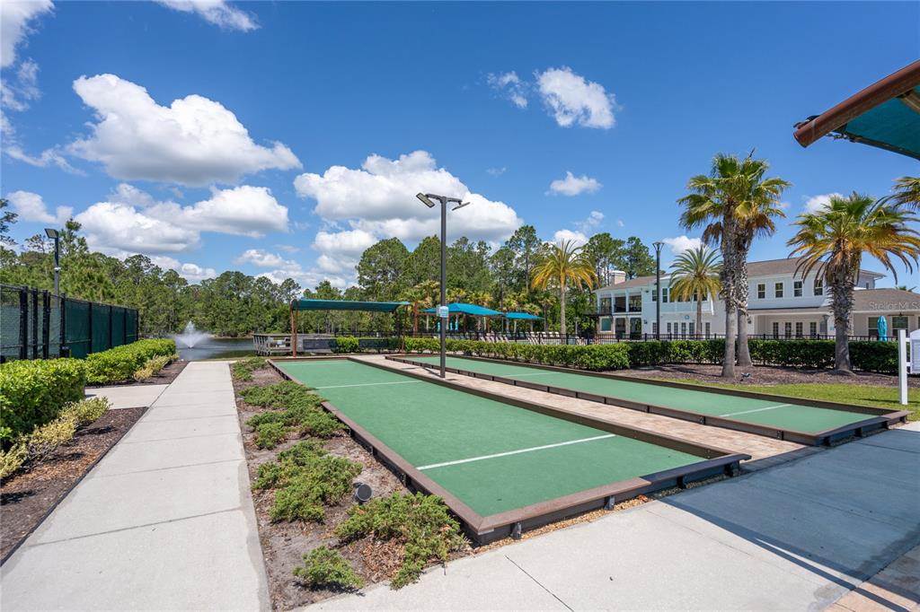 Two outdoor bocce ball courts are situated next to a paved walkway and a pond — 606 GRAND RESERVE DRIVE, BUNNELL, FL