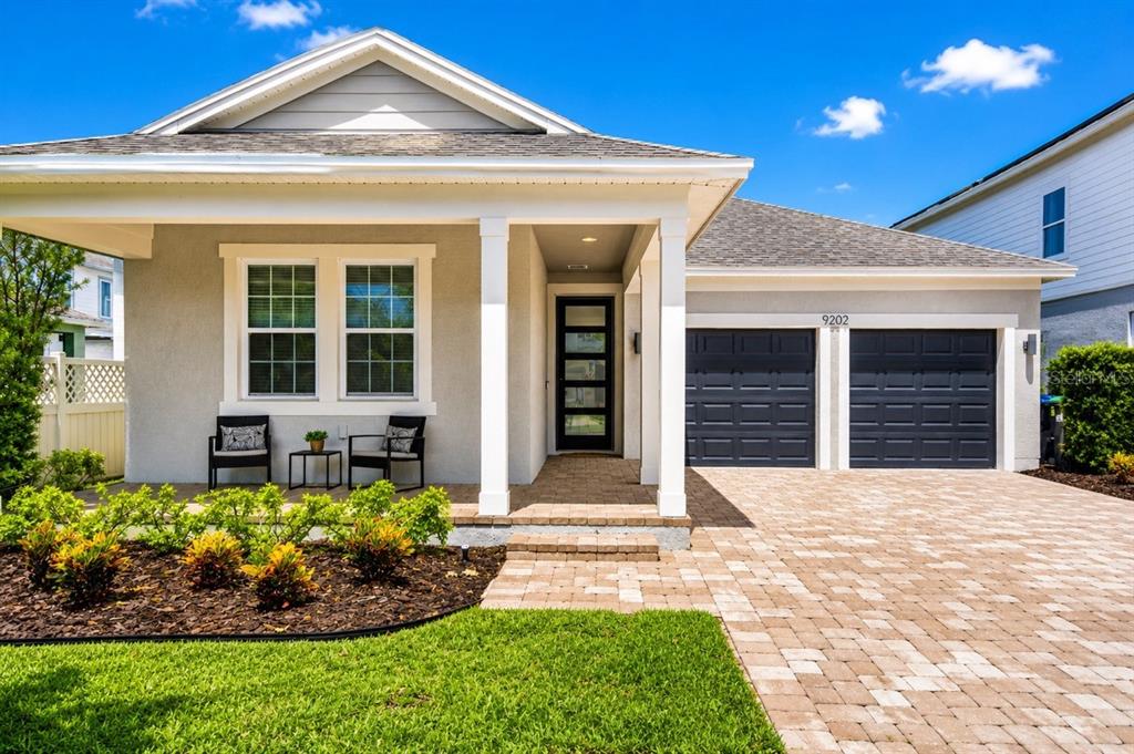 A single-story house with a gray stucco exterior, a paved driveway, and a front porch — 9202 MERLON DRIVE, WINTER GARDEN, FL