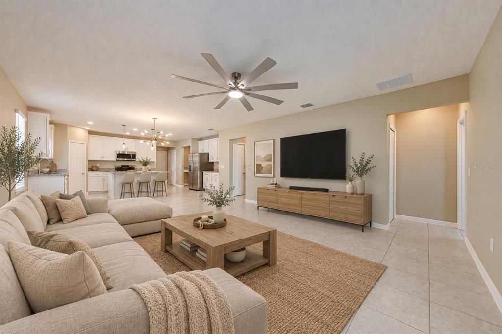 A spacious open-concept living room features a large sectional sofa, wood coffee table, and television — 352 BRIARBROOK LANE, HAINES CITY, FL