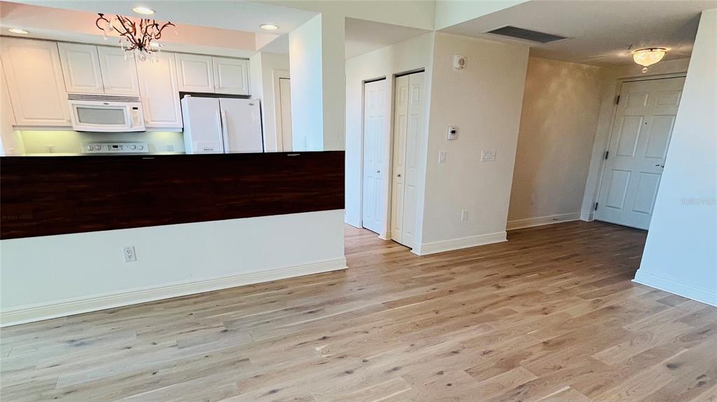 A kitchen with white cabinets and a dark wood breakfast bar overlooks a living area — 800 N TAMIAMI TRAIL UNIT 205, SARASOTA, FL
