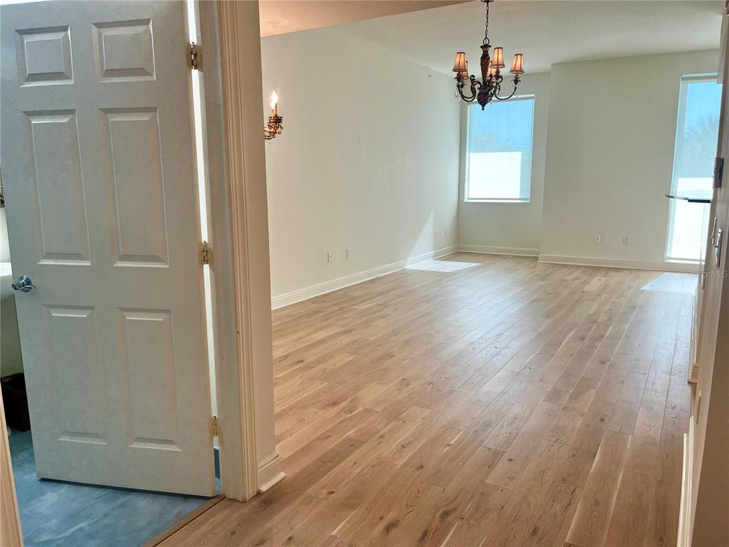 An interior view shows a dining area with light wood flooring and a hanging chandelier — 800 N TAMIAMI TRAIL UNIT 205, SARASOTA, FL