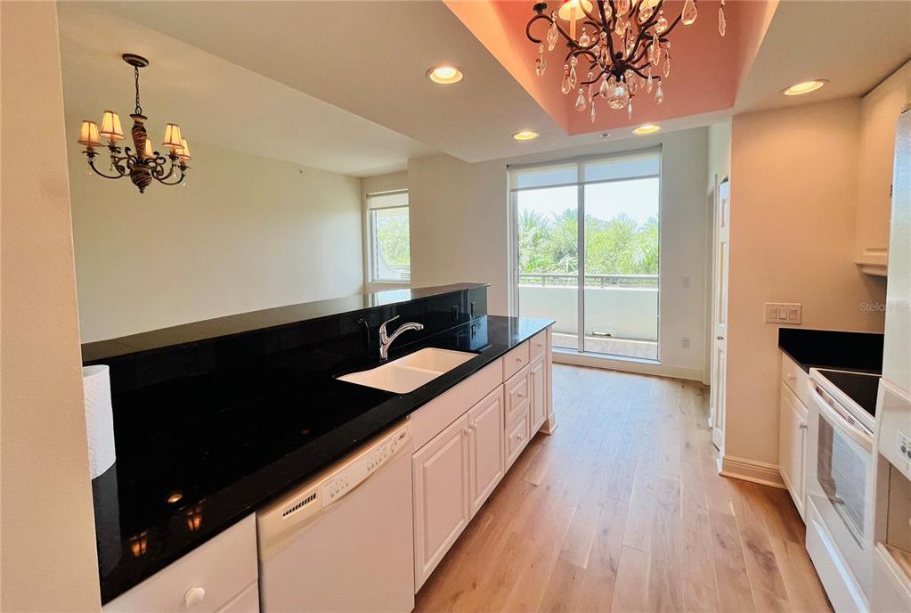 A kitchen with white cabinets, black countertops, and a chandelier over the breakfast bar area — 800 N TAMIAMI TRAIL UNIT 205, SARASOTA, FL