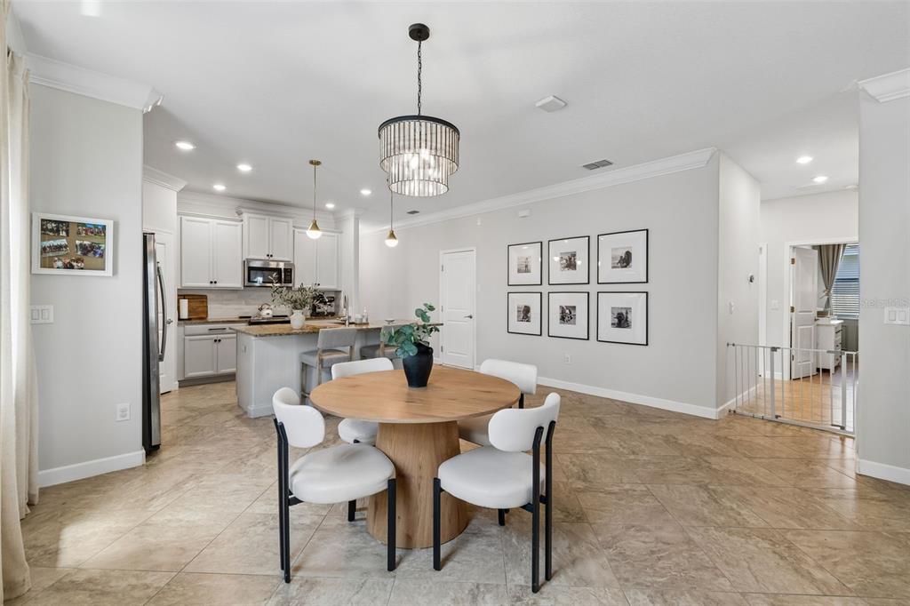 A bright kitchen and dining area featuring a round wooden table and white chairs — 13170 GREEN VIOLET DRIVE, RIVERVIEW, FL