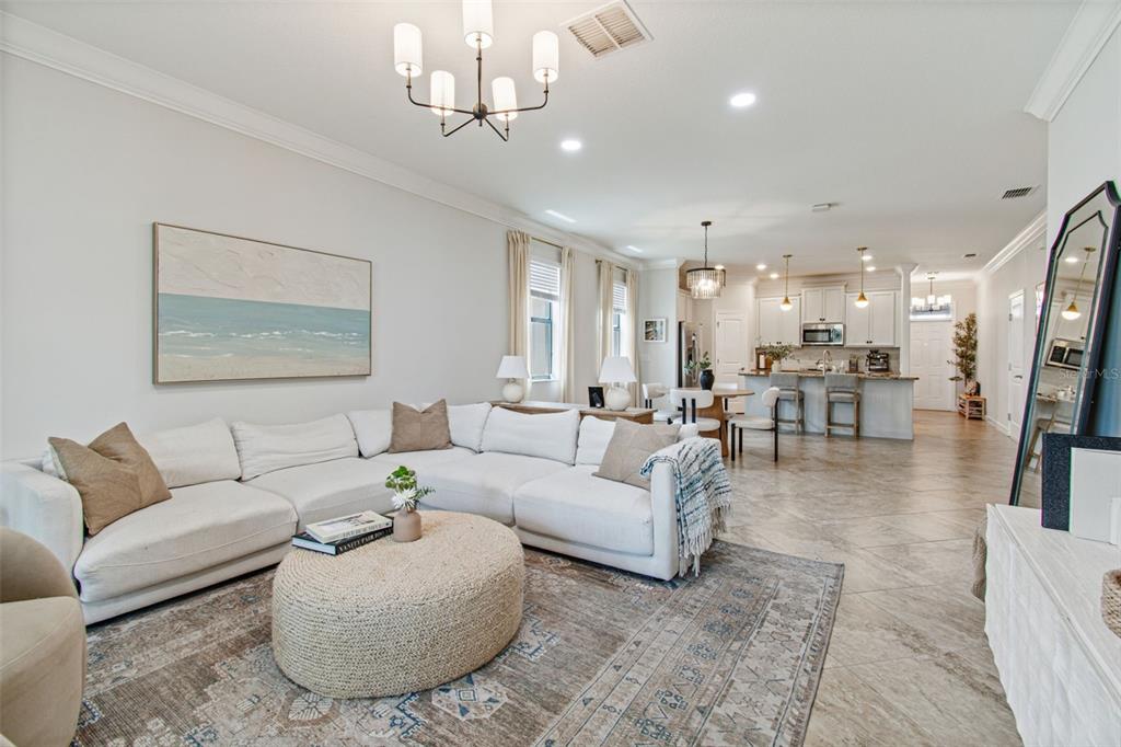 A bright open-concept living room and kitchen featuring a large sectional sofa and tile flooring — 13170 GREEN VIOLET DRIVE, RIVERVIEW, FL