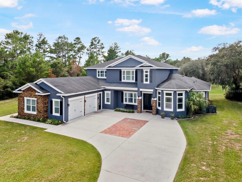 A two-story blue house with a stone accent wall, attached garage, and paved driveway — 2630 FRANKLIN ROAD, ST CLOUD, FL