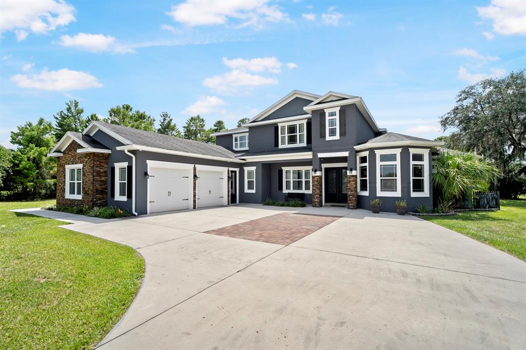 A two-story gray house with a stone accent wall, a three-car garage, and a driveway — 2630 FRANKLIN ROAD, ST CLOUD, FL