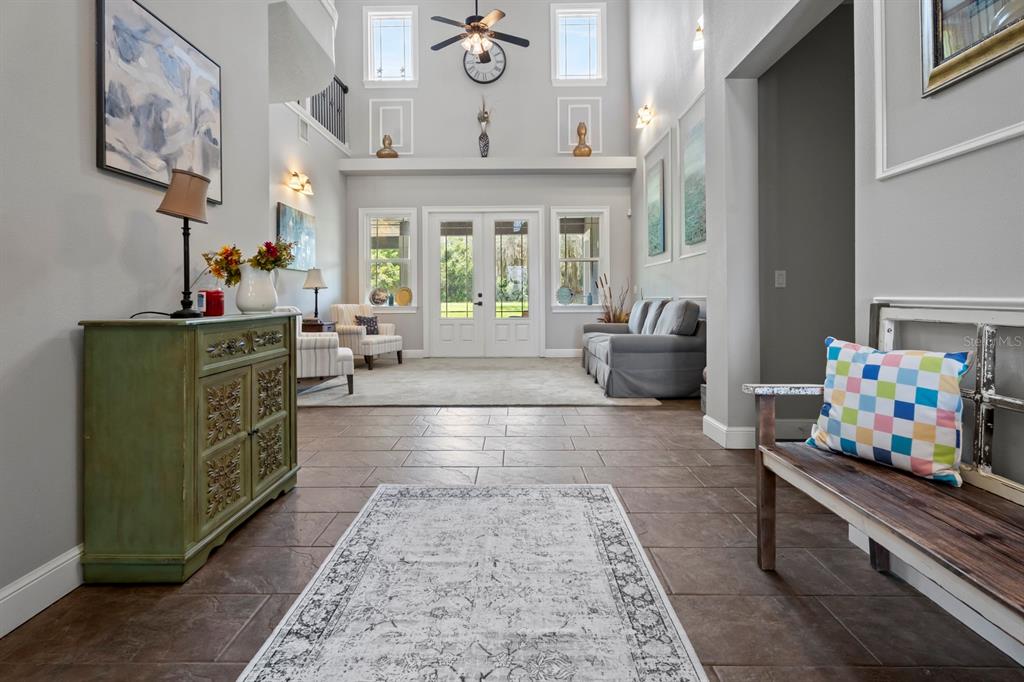 A spacious entryway features tile flooring, a green cabinet, a bench, and a high ceiling — 2630 FRANKLIN ROAD, ST CLOUD, FL