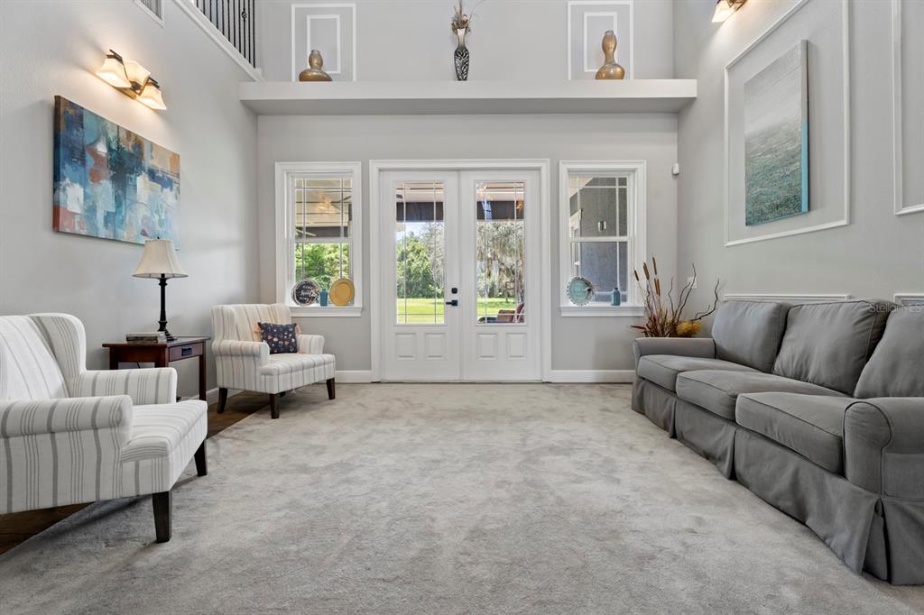 A living room features a high ceiling, gray carpet, a gray sofa, and two striped chairs — 2630 FRANKLIN ROAD, ST CLOUD, FL