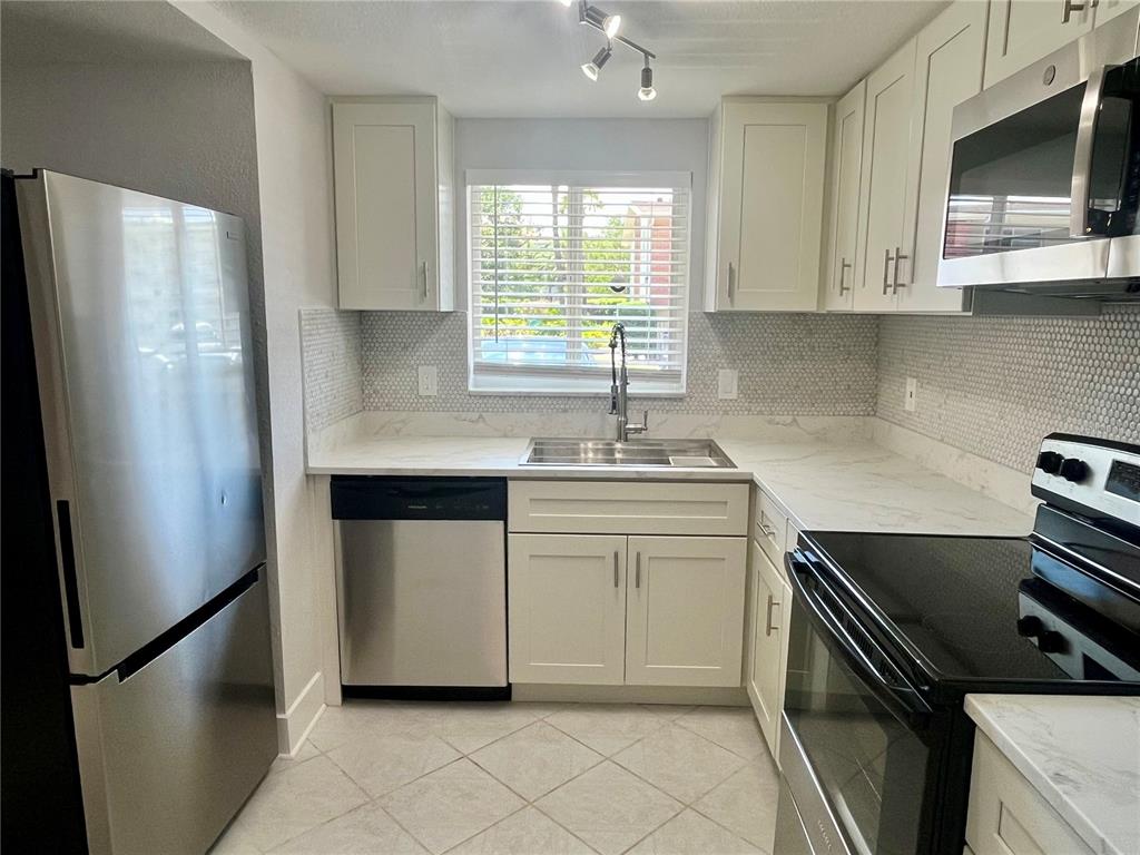 A kitchen features white cabinets, stainless steel appliances, a marble-look countertop, and a tiled backsplash — 4550 OVERLOOK DRIVE NE UNIT 156, ST PETERSBURG, FL