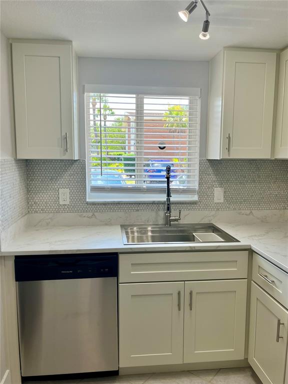 A kitchen features white cabinets, a stainless steel dishwasher, and a marble-patterned countertop — 4550 OVERLOOK DRIVE NE UNIT 156, ST PETERSBURG, FL