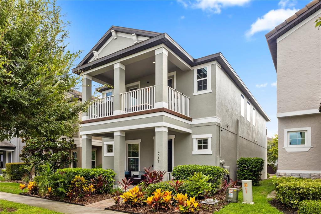 A two-story house with a front porch, a second-floor balcony, and landscaped front yard — 14536 GOLDEN HARBOR LANE, WINTER GARDEN, FL
