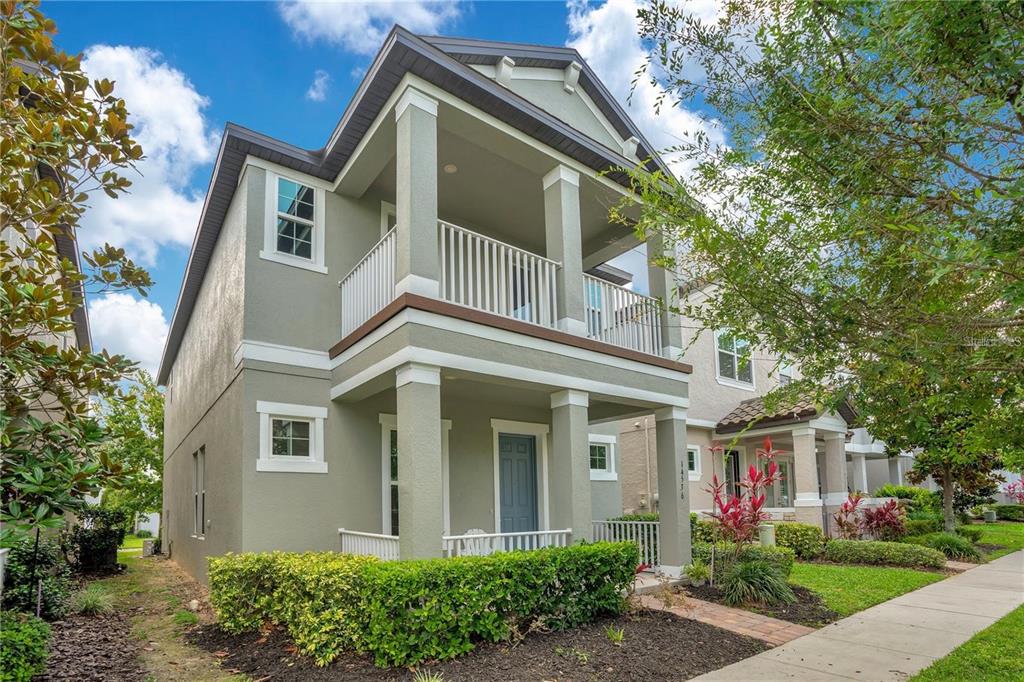 A two-story house with a front porch, a second-floor balcony, and a manicured hedge — 14536 GOLDEN HARBOR LANE, WINTER GARDEN, FL