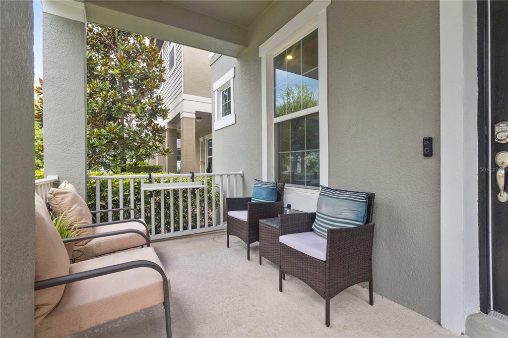A covered porch features a concrete floor, white railings, and four outdoor chairs — 14536 GOLDEN HARBOR LANE, WINTER GARDEN, FL