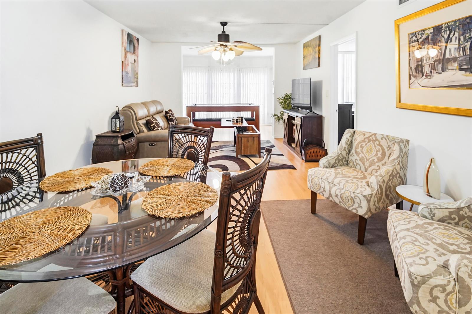A dining area with a glass table flows into a living room with patterned chairs — 6650 Royal Palm Boulevard # 104c, Margate FL 33063, MARGATE, FL