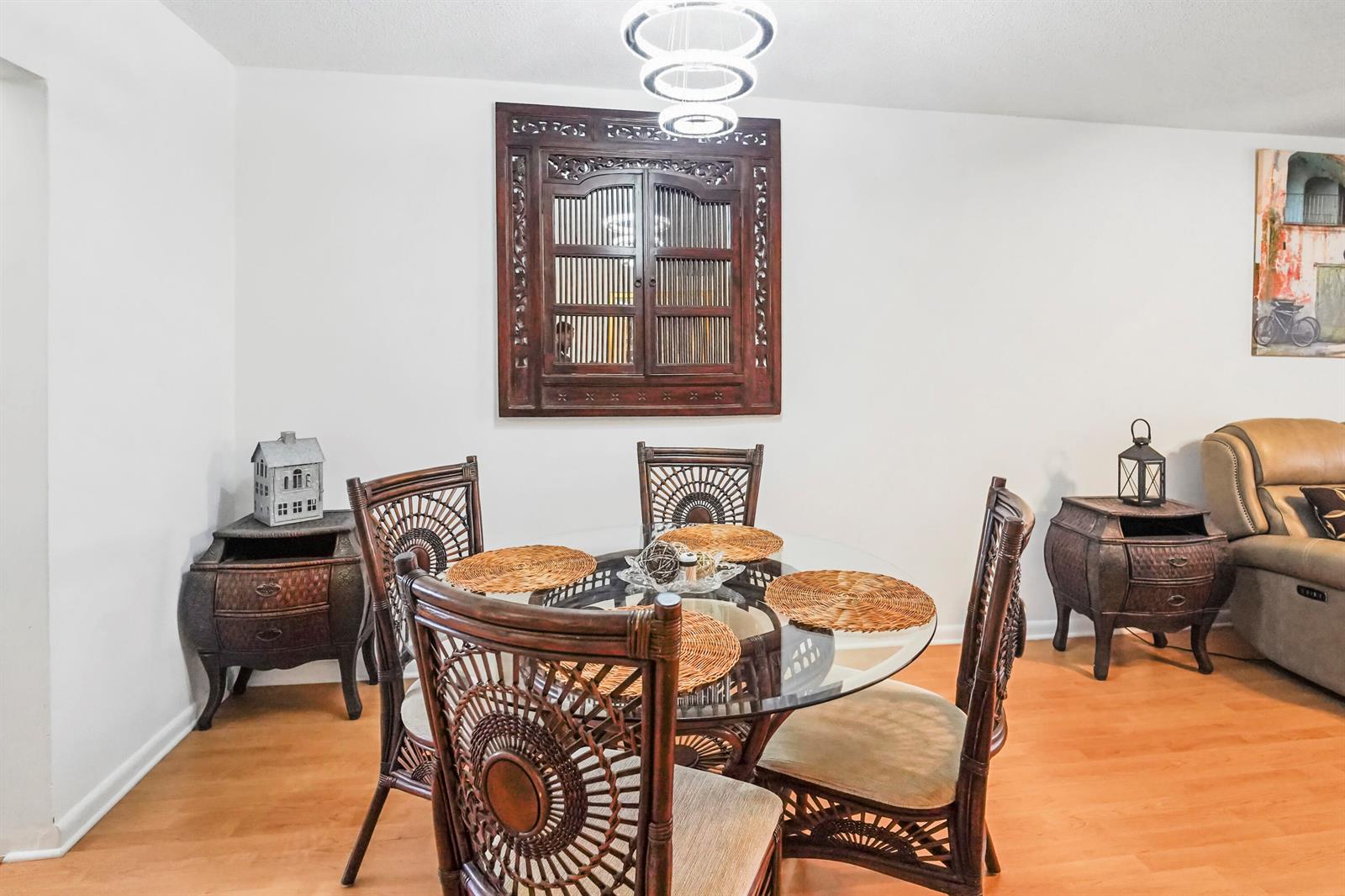 A dining room features a glass-topped table, wicker chairs, and a decorative wooden wall hanging — 6650 Royal Palm Boulevard # 104c, Margate FL 33063, MARGATE, FL