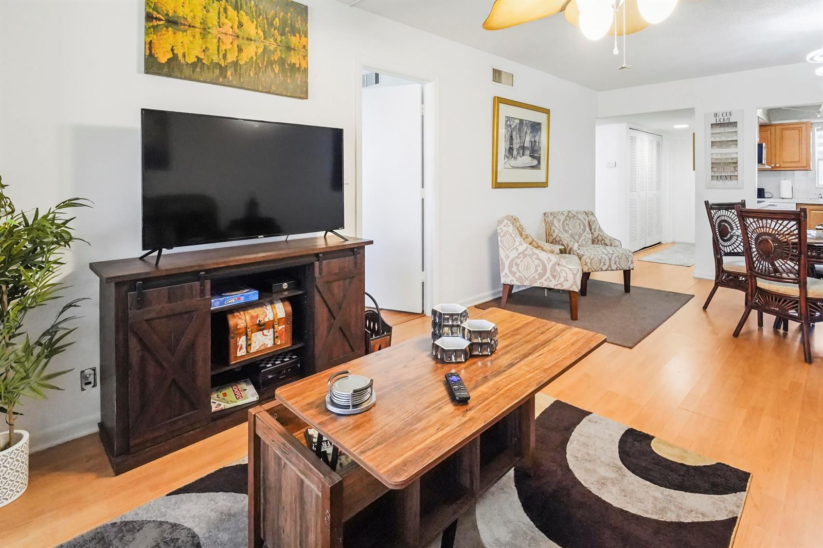 A living room features a wooden media console, a coffee table, and patterned armchairs — 6650 Royal Palm Boulevard # 104c, Margate FL 33063, MARGATE, FL