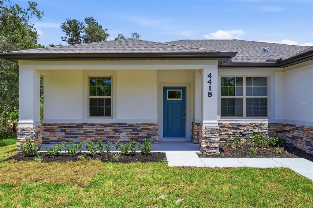 A single-story house exterior features a blue front door, stone veneer, and a covered porch — 4418 PONCE DE LEON BOULEVARD, NORTH PORT, FL