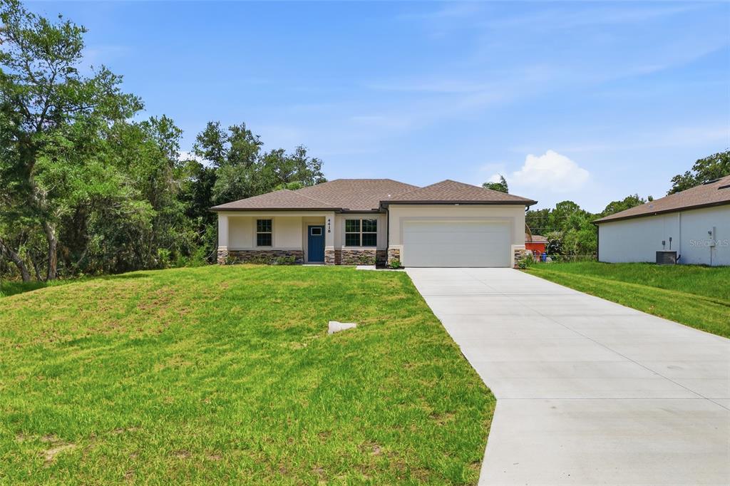 A single-story house with a beige stucco exterior, stone accents, and a two-car garage — 4418 PONCE DE LEON BOULEVARD, NORTH PORT, FL