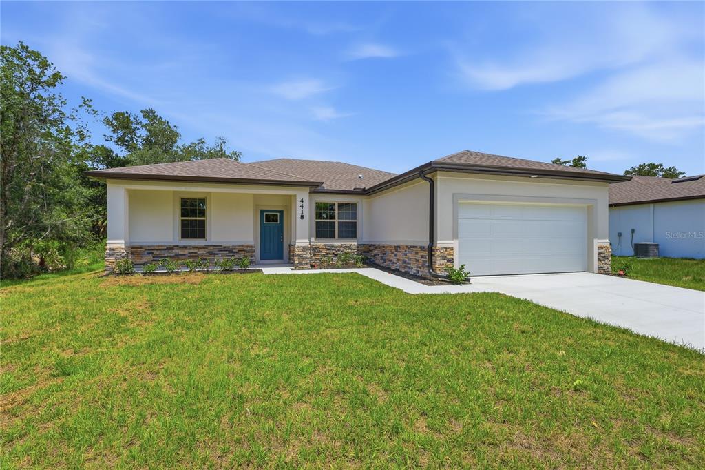 A single-story house with a stone-accented facade, blue front door, and a two-car garage — 4418 PONCE DE LEON BOULEVARD, NORTH PORT, FL