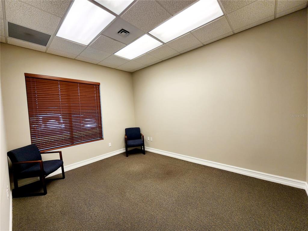 An office room features two dark chairs, a window with blinds, and carpeted flooring — 1016 COLLIER CENTER WAY UNIT 106, NAPLES, FL