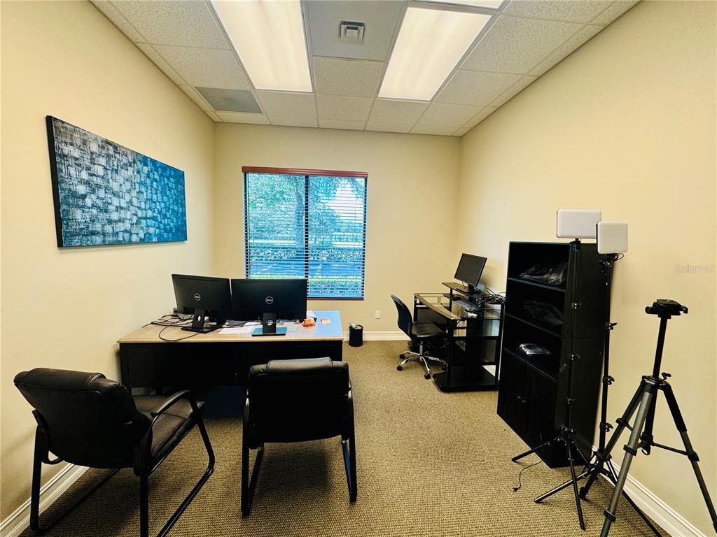An office room features two desks, chairs, a black shelving unit, and a window — 1016 COLLIER CENTER WAY UNIT 106, NAPLES, FL