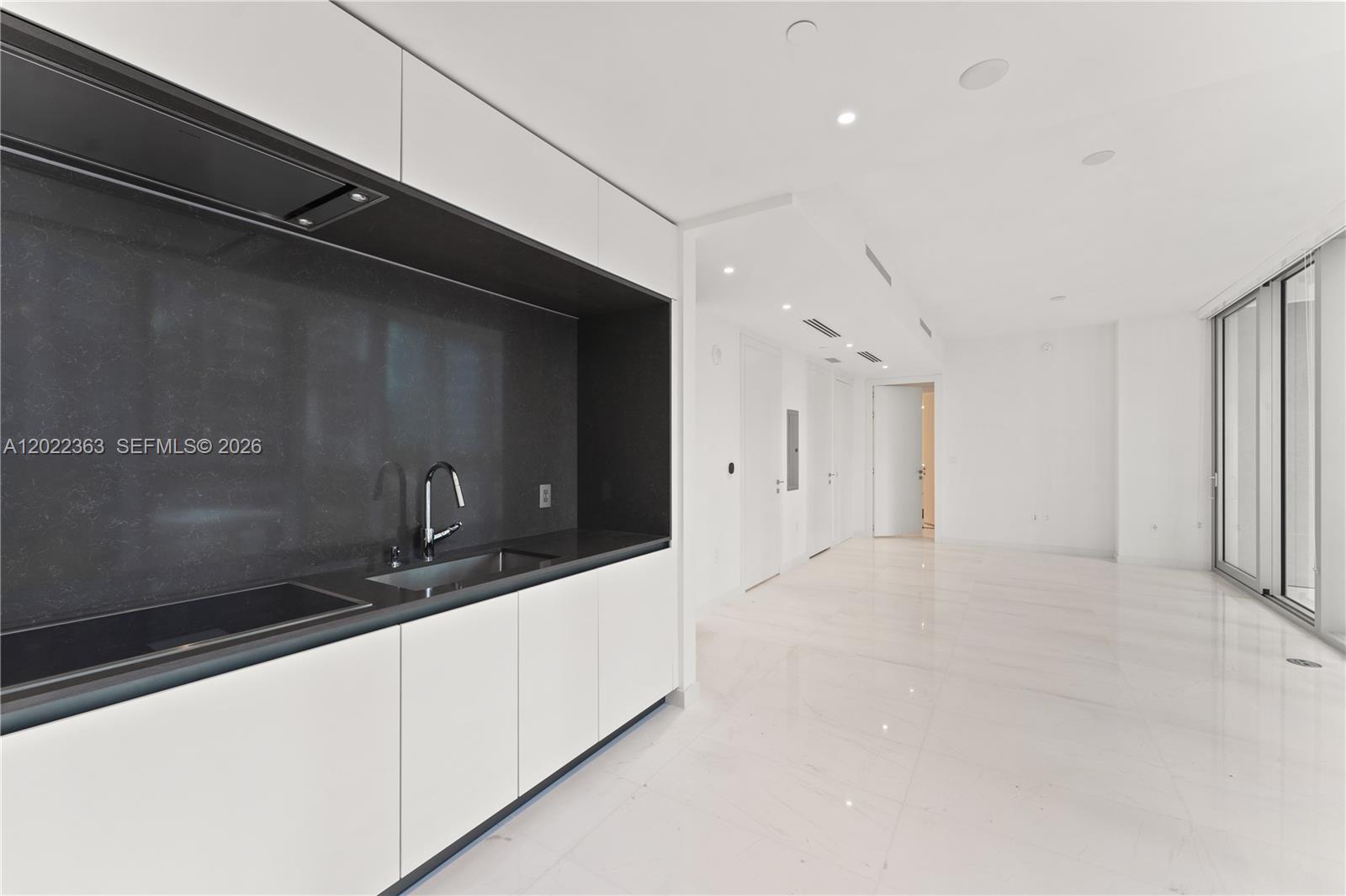A modern kitchen features white cabinets, a dark stone backsplash, and white tile flooring — 300 Biscayne Blvd Way # 1406, Miami FL 33131, MIAMI, FL