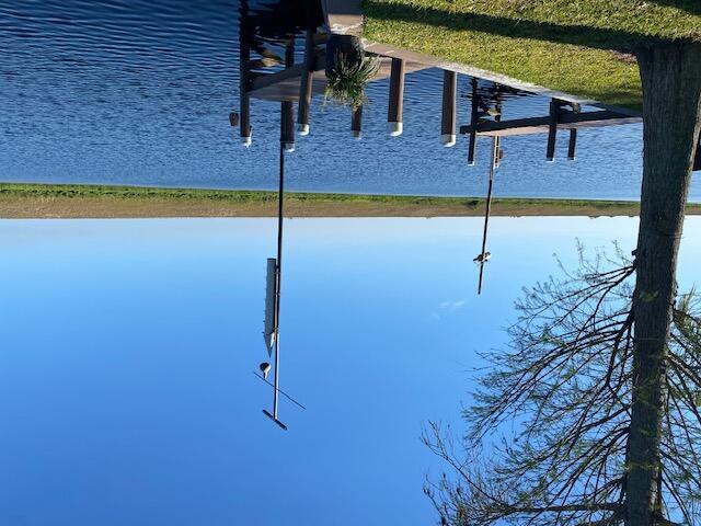 A wooden dock extends into a calm canal under a clear blue sky — 8680 Us Highway 441 SE, Okeechobee FL 34974, OKEECHOBEE, FL