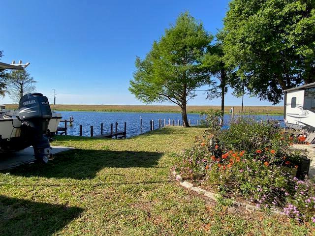 A boat docked near a grassy yard with a flower garden and a nearby camper — 8680 Us Highway 441 SE, Okeechobee FL 34974, OKEECHOBEE, FL