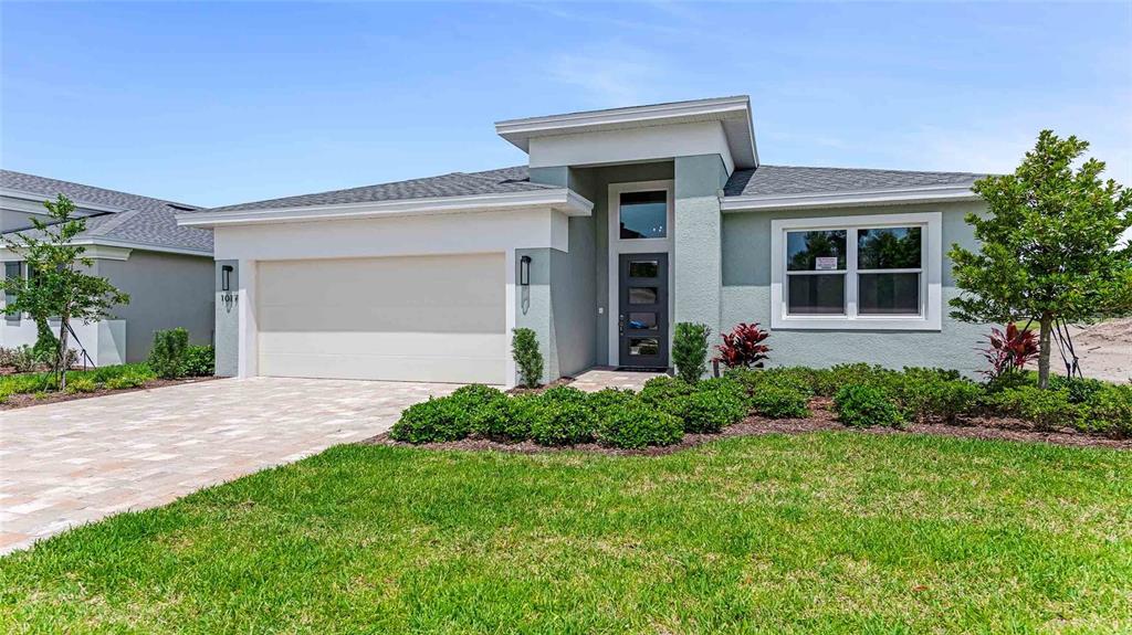 A single-story house with a light green stucco exterior, a two-car garage, and landscaping — 1017 LILIANA DRIVE, DELAND, FL