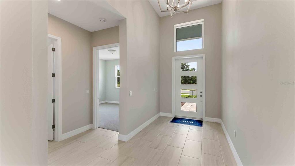 A bright entryway features light tile flooring, a high ceiling, and a white front door — 1017 LILIANA DRIVE, DELAND, FL