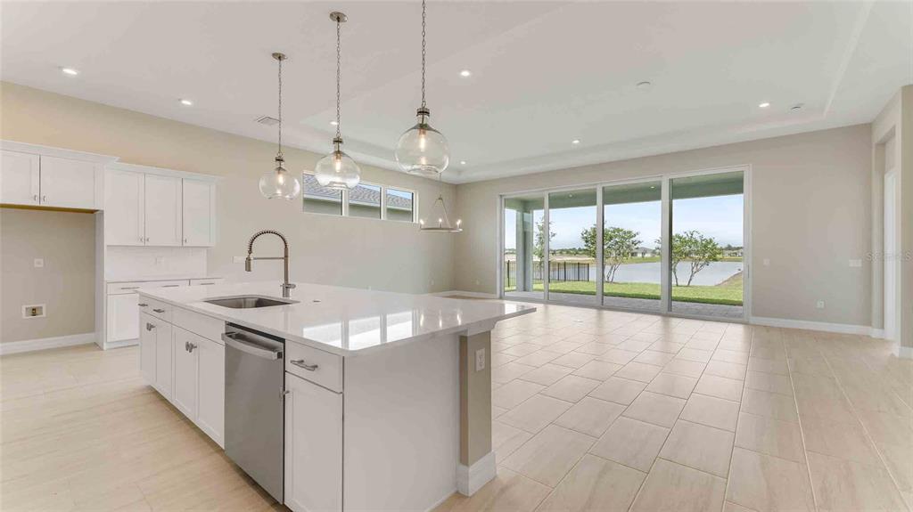 A modern kitchen with a white island and quartz countertops overlooks a lake through sliding doors — 1017 LILIANA DRIVE, DELAND, FL