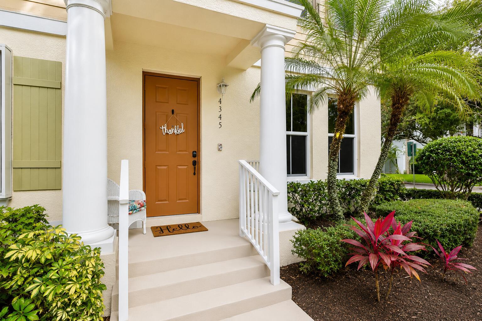 A tan house exterior features a brown front door, white columns, and a small porch — 4345 Parkside Drive, Jupiter FL 33458, JUPITER, FL