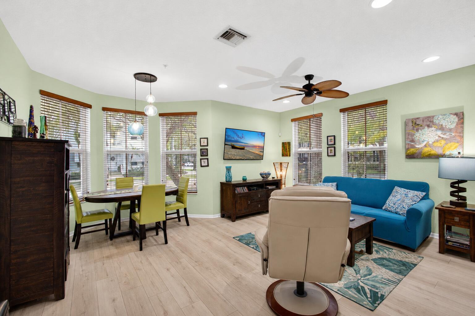 A living and dining area with light green walls, wood-look flooring, and a blue sofa — 4345 Parkside Drive, Jupiter FL 33458, JUPITER, FL