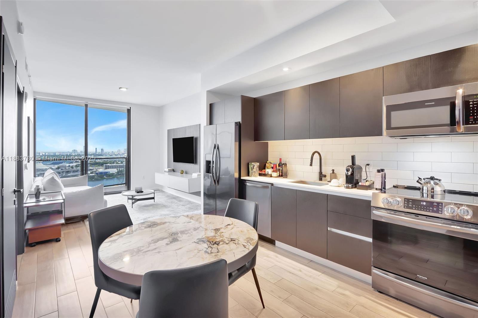 A modern open-concept kitchen and living area features dark cabinetry, marble-topped table, and city views — 398 NE 5th St # 1910, Miami FL 33132, MIAMI, FL