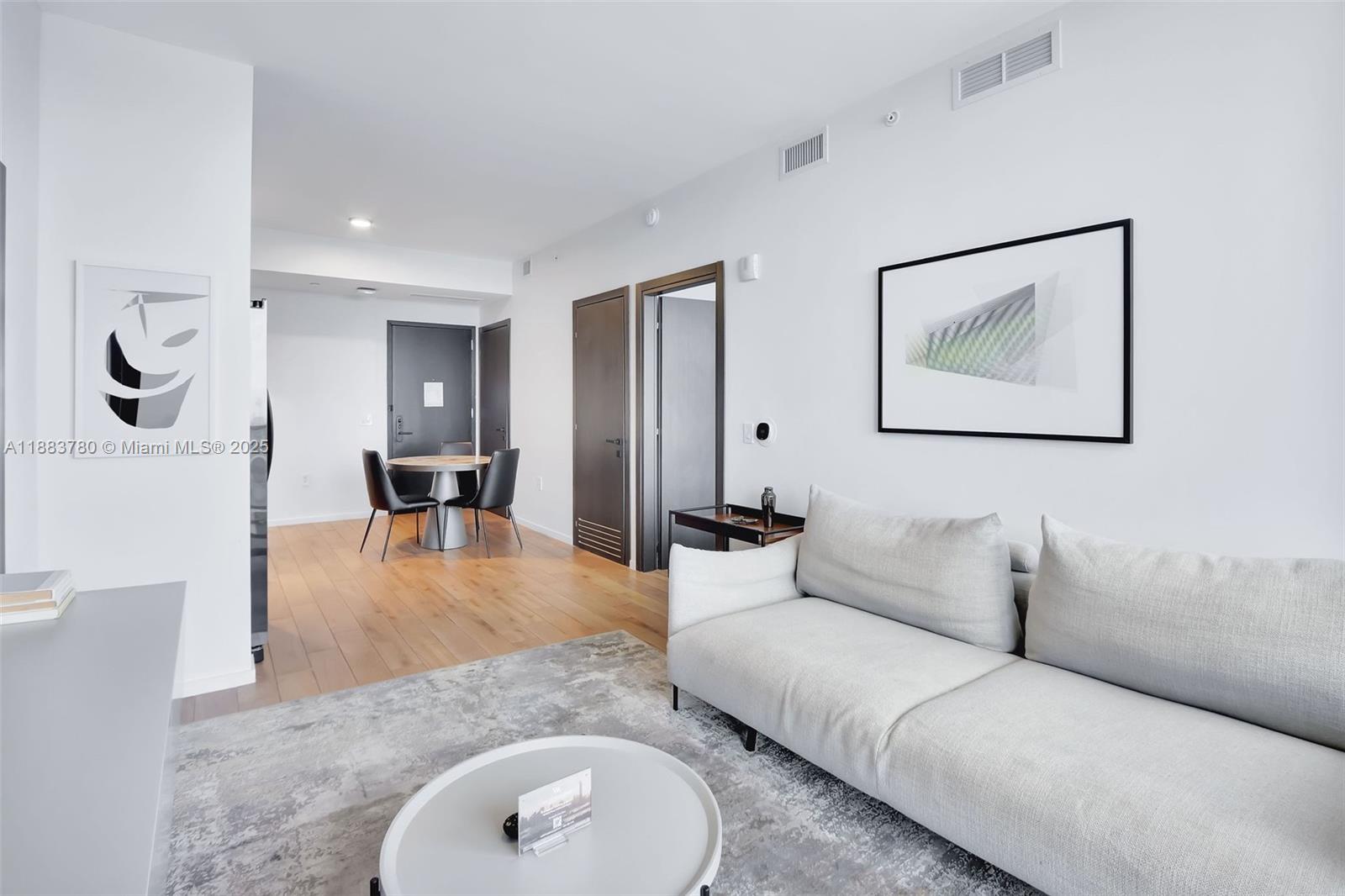 A modern living room features a light gray sofa, a round coffee table, and hardwood floors — 398 NE 5th St # 1910, Miami FL 33132, MIAMI, FL
