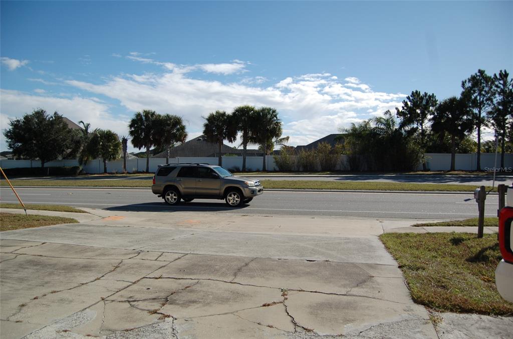 A tan SUV drives on a road in front of a white fence and trees — 223 COUNTY ROAD 466A, FRUITLAND PARK, FL