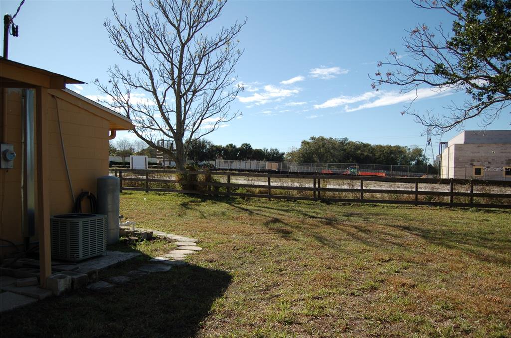 A backyard with a wooden fence, a yellow house exterior, and a large bare tree — 223 COUNTY ROAD 466A, FRUITLAND PARK, FL