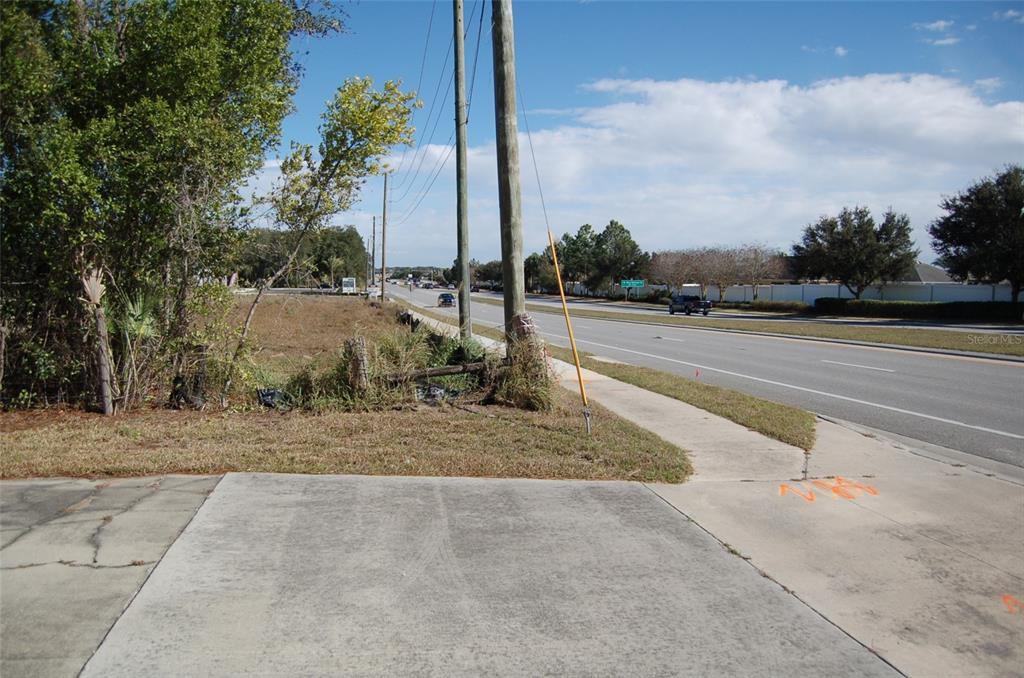 A paved driveway leads to a grassy lot beside a multi-lane road with utility poles — 223 COUNTY ROAD 466A, FRUITLAND PARK, FL