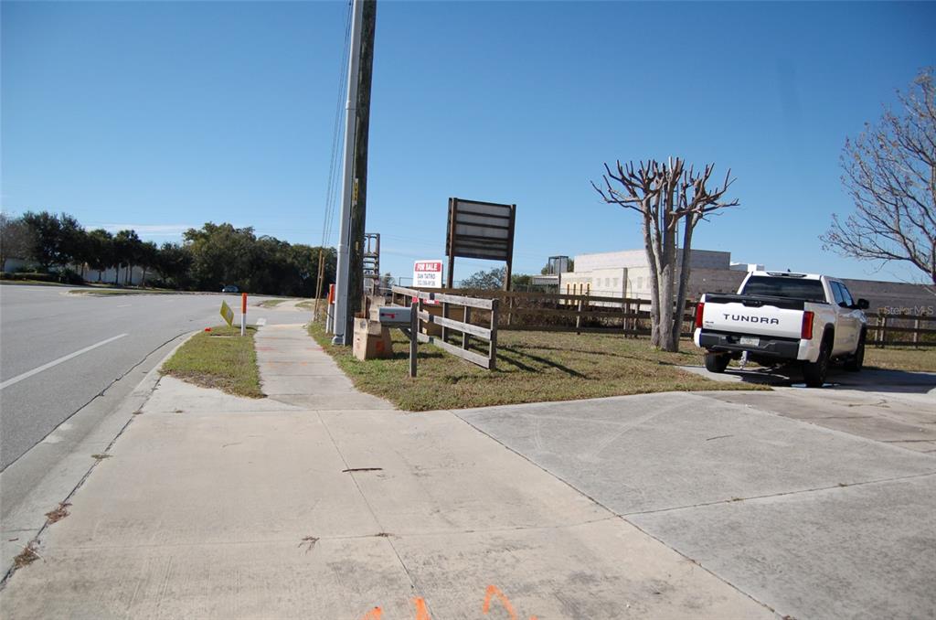 A white pickup truck is parked on a grassy lot next to a sidewalk — 223 COUNTY ROAD 466A, FRUITLAND PARK, FL
