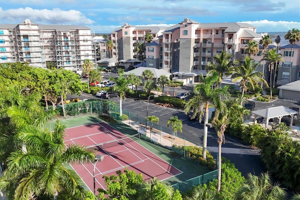 An aerial view of a tennis court next to multi-story apartment buildings and parking — 13113 GASPARILLA ROAD UNIT 403, PLACIDA, FL