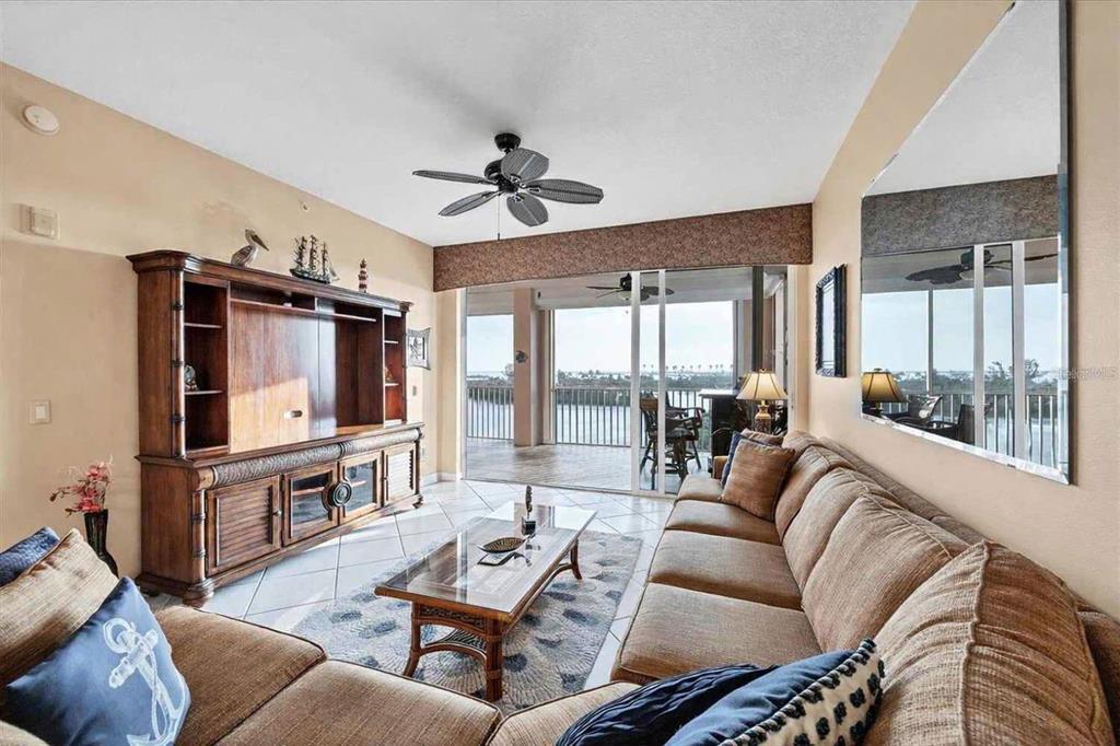 A living room features a large wooden entertainment center, a sectional sofa, and a balcony — 13113 GASPARILLA ROAD UNIT 403, PLACIDA, FL