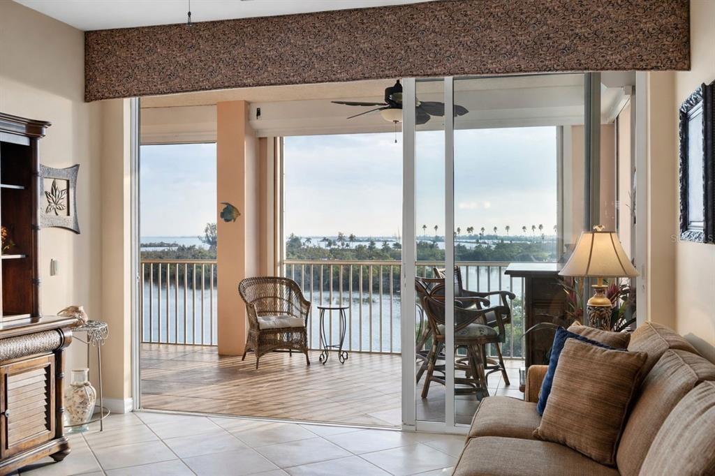 A living room with tile floors opens through sliding glass doors to a balcony overlooking water — 13113 GASPARILLA ROAD UNIT 403, PLACIDA, FL