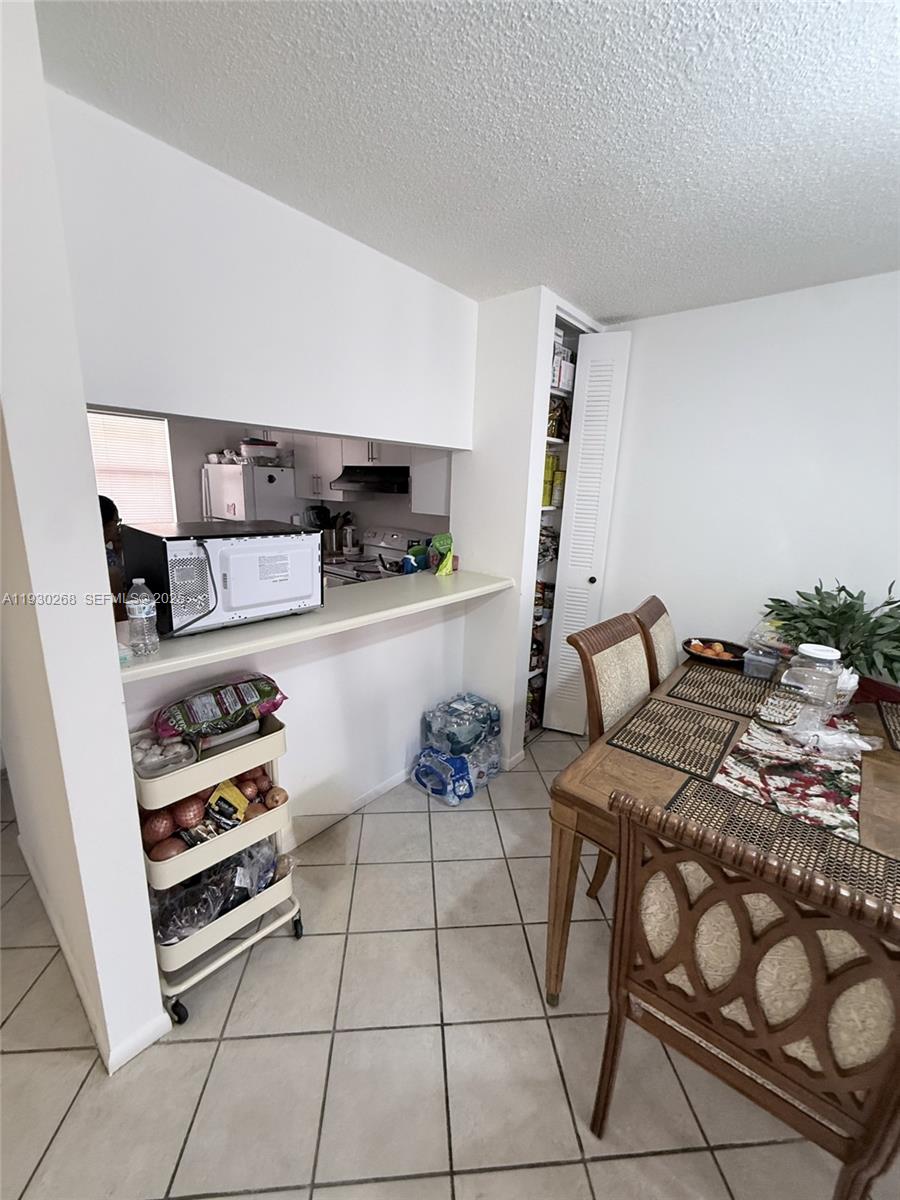 A kitchen pass-through overlooks a dining area with a table, chairs, and a pantry closet — 19715 SW 114th Ave # 258, Miami FL 33157, MIAMI, FL