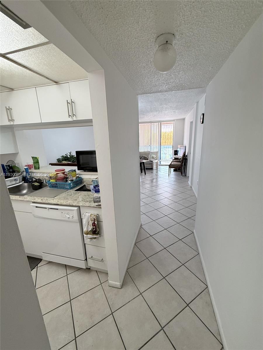 A view from a tiled hallway looking into a kitchen and a living area beyond — 19715 SW 114th Ave # 258, Miami FL 33157, MIAMI, FL
